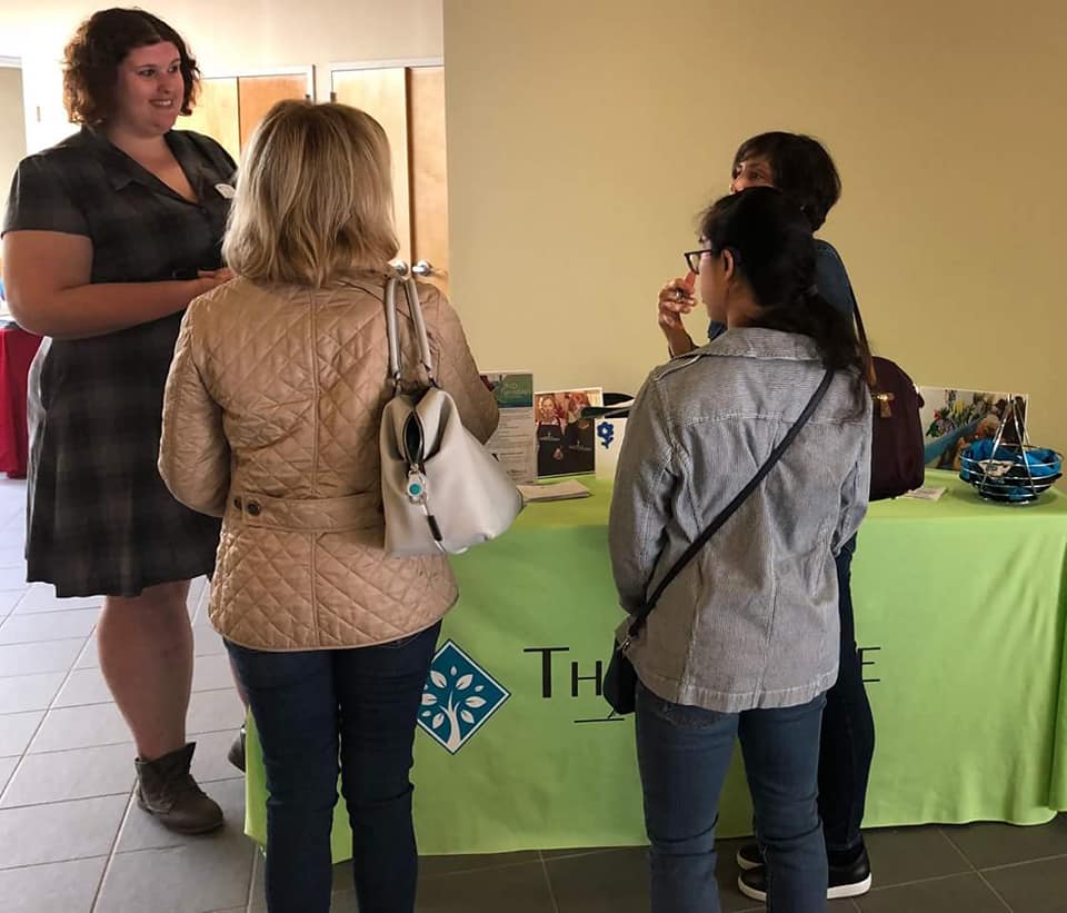 Representative speaking with three individuals at an informational table during a family resource event.