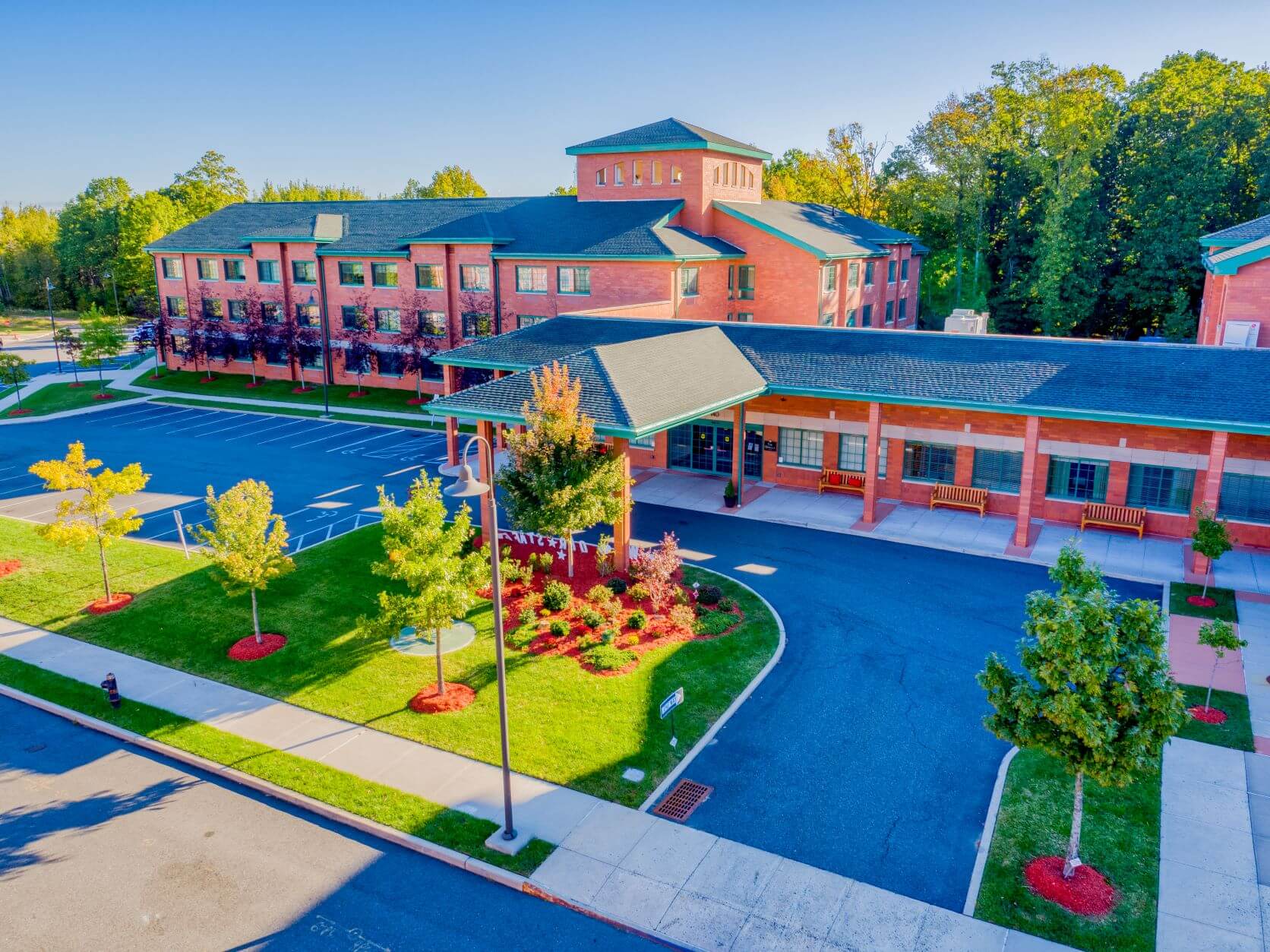 Aerial view of The Brielle senior living community with landscaped gardens, trees, and parking spaces.