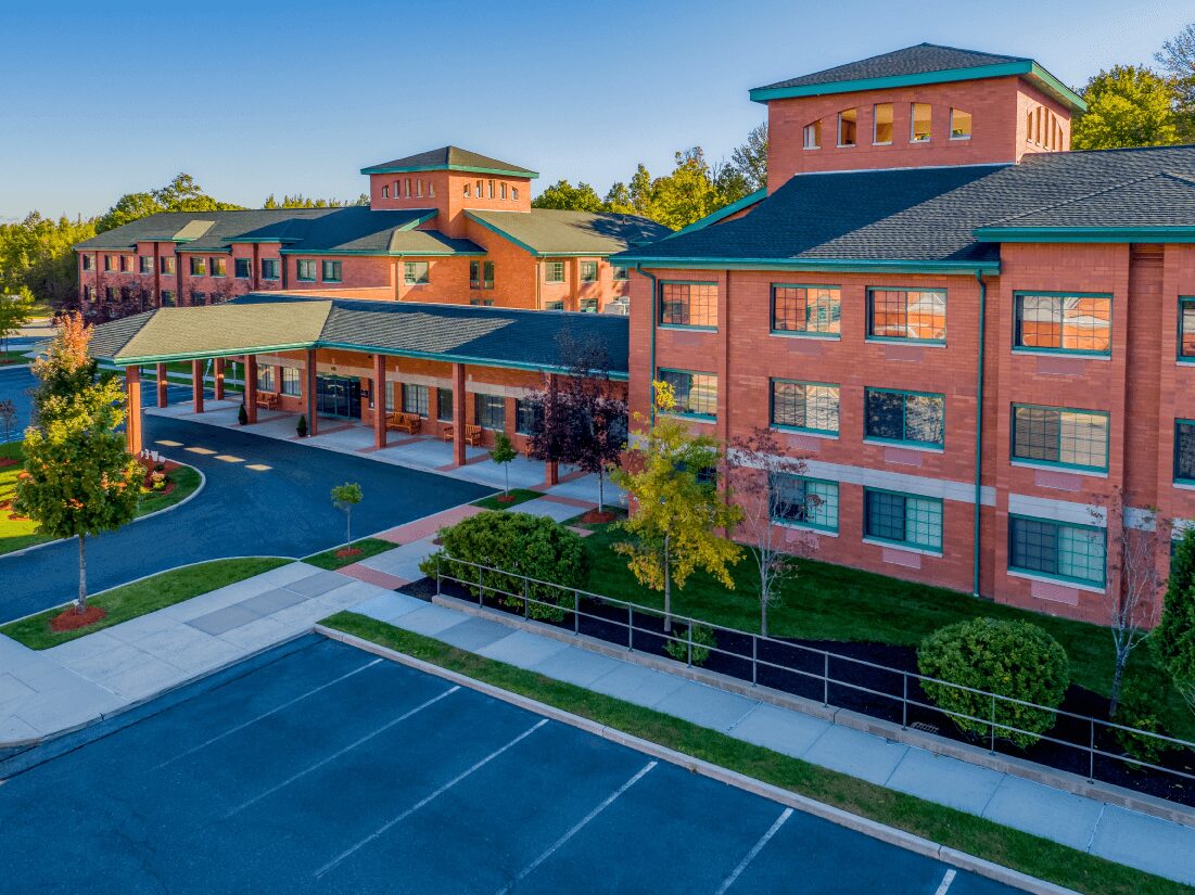 The Brielle Community Exterior Exterior view of a brick senior living community with parking lot and landscaped areas.