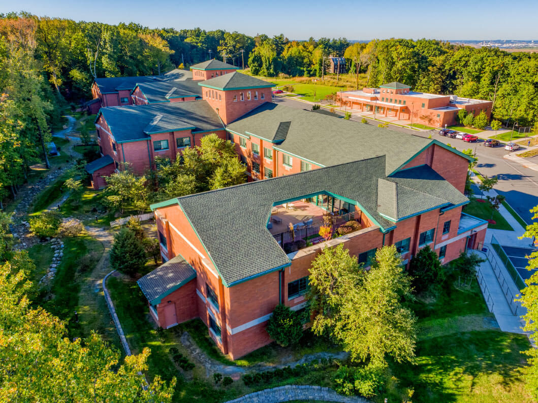 Aerial view of a senior living community building surrounded by greenery and trees.