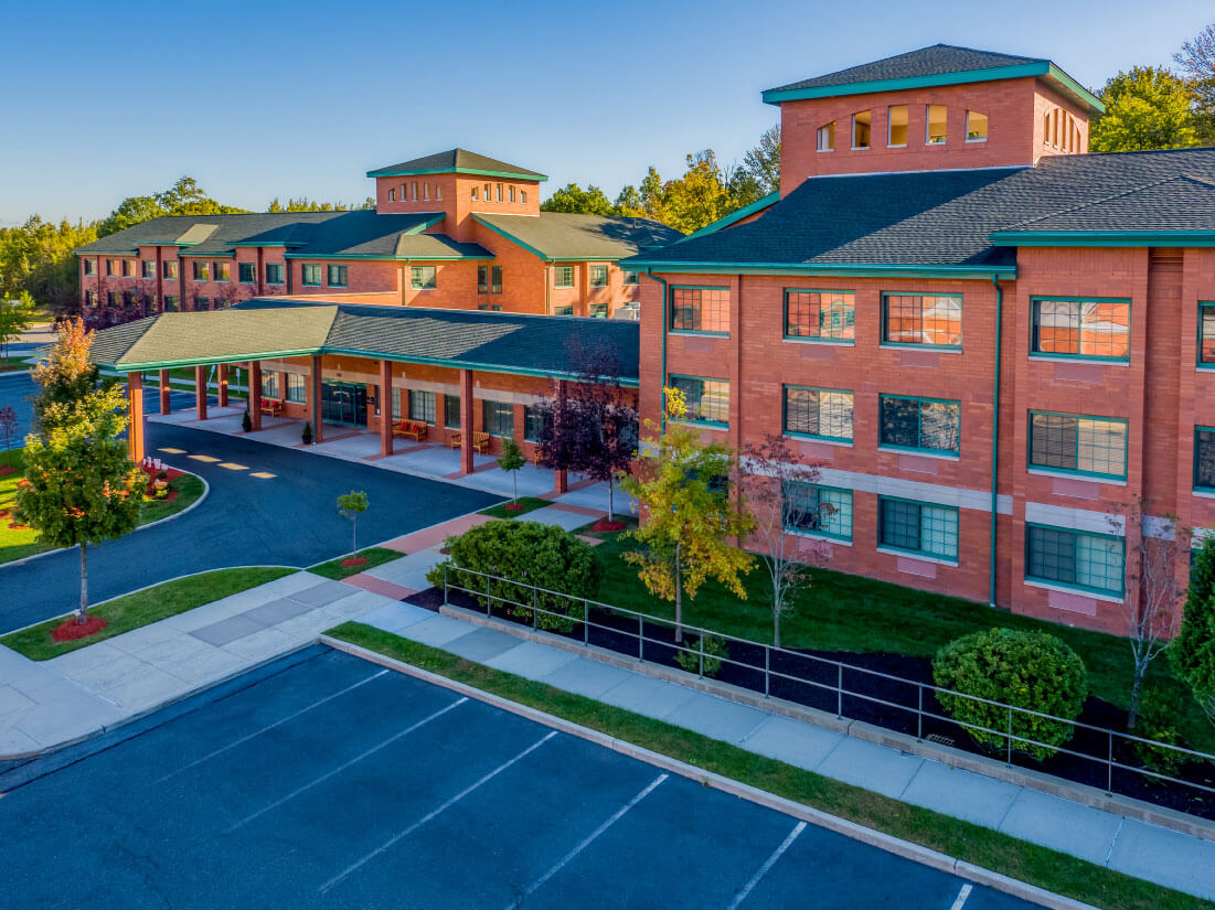 Exterior view of Brielle Community entrance with greenery and parking area.