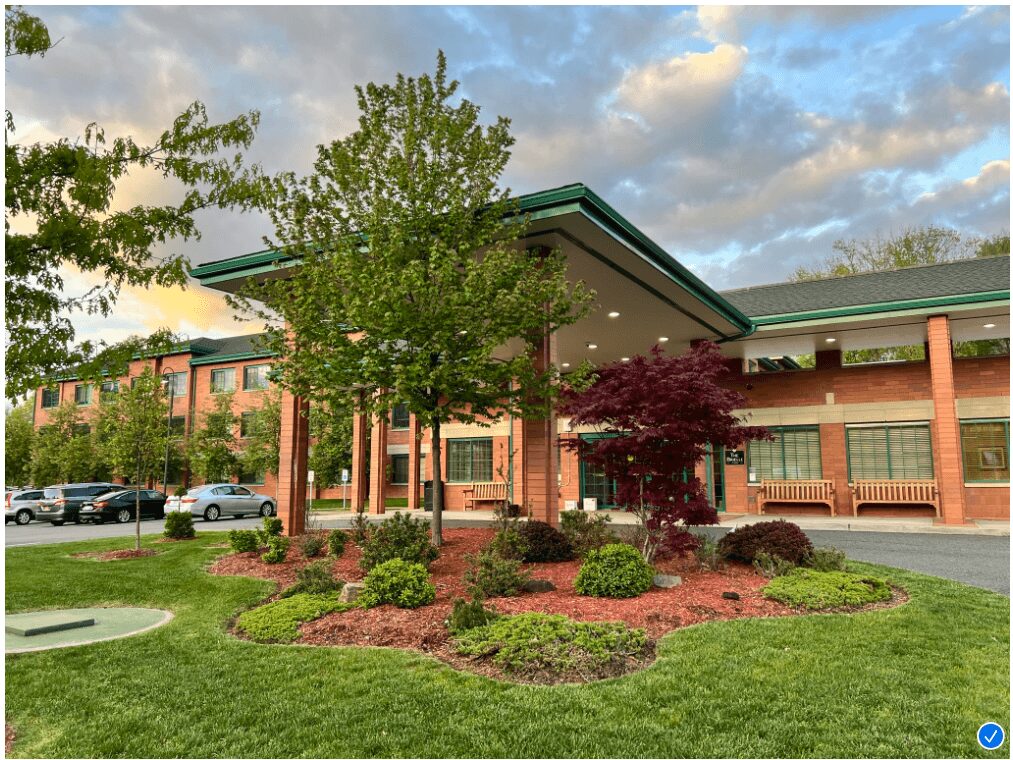 Exterior view of a senior living community with lush landscaping and a modern entrance.