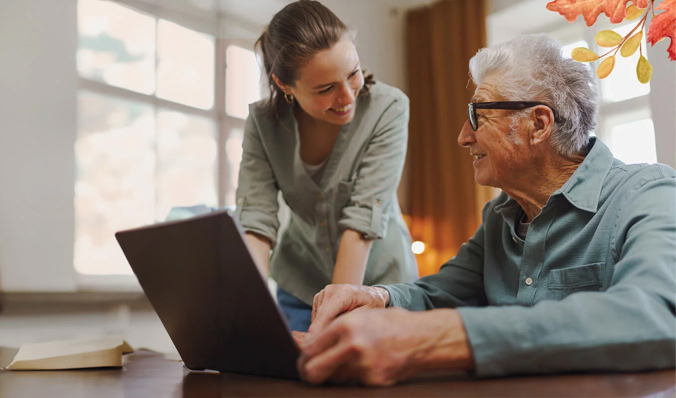 Senior man and young woman look at computer together