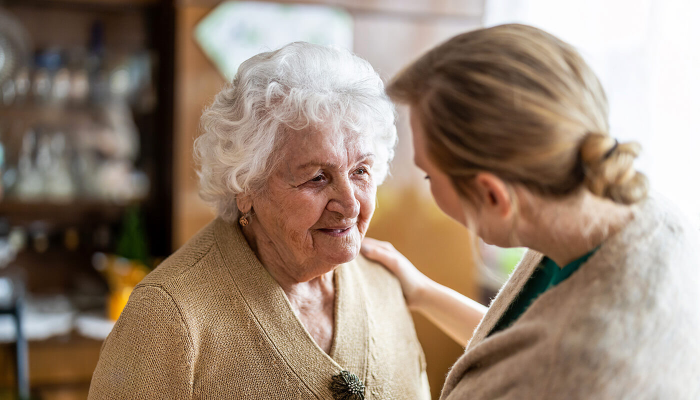 Senior man smiles at female caregiver